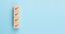 Checklist concept, Check mark on wooden blocks, blue background with copy space