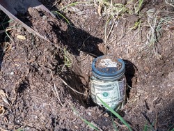 Burying a jar of money in the garden as savings, retirement or college fund concept.