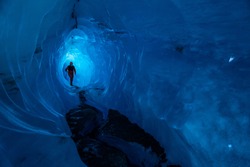 A guide walks through the tunnel of a glacier ice cave on the Matanuska Glacier in Alaska. Carved by water from melting ice, the tunnel goes deep into the glacier.