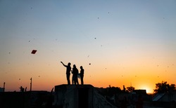 People playing kites in the rooftop during sunset