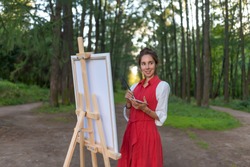 Wonderful artist, Alley trees background. Beautiful woman in red dress in summer in park and forest, draws a picture, creating creativity and landscape. Girl creativity and art concept
