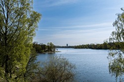 Landscape. Lake in spring, green trees, blue water and blue sky.