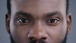 Close-up of beautiful black man eyes staring at camera. Portrait detail of serious confident african american man.