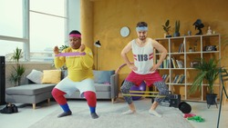 Sports parody. Comical funny unfit retro looking young men training with resistance bands doing wrong exercises having fun home workout.