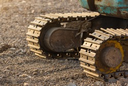 Track shoe of the excavator with soil in the background.