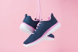 Female sneakers for run on pink background. Fashion stylish sport shoes, close up