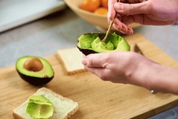 Woman hold fresh ripe avocado and peeling it with spoon, Healthy food and dieting concept, Organic product