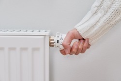 Woman adjusting temperature on heating radiator, Energy crisis concept in Europe, Rising costs in private households for gas bill due to inflation and war