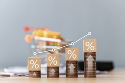 Interest on stack of coins stacked on table with percentage icon on wooden wooden block with white illustration showing interest rate increase financial concept.