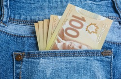 Canadian banknotes are in the back pocket of blue jeans.