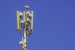 5G smart cellular network antenna base station on the telecommunication mast on blue sky background. Telecommunication tower of 4G and 5G cellular on blue sky background