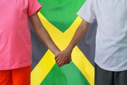 Two afro children joined hands on flag Jamaica background. Boy and girl joined hands on background flag of Jamaica. Concept of family and parenting in Jamaica