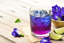 Butterfly pea or blue pea juice ice cool drink with lime on wooden table.