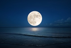 Full moon over the sea with sea wave on sandy beach. (Elements of the moon image furnished by NASA)