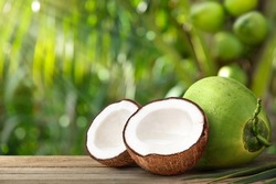 Coconut fruit cut in half with coconut tree background.