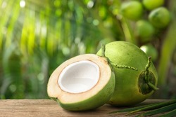 Coconut juice in half fruit with coconut tree background.