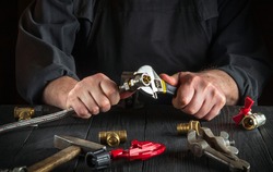 Master plumber connects the brass fittings to the faucet with an adjustable wrench. Close-up of a foreman is hands while working in a workshop