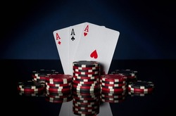 Poker game with three of kind or set combination. Chips and cards on black table. Successful and win three aces