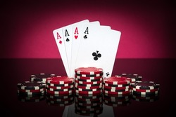 Playing cards in poker game with four of a kind or quads combination. Chips and cards on black table. Successful and win.