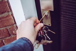 Hand opening house door with bunch of keys