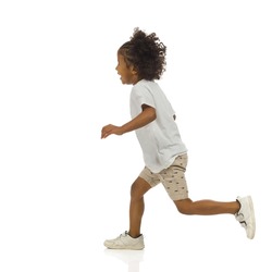 Running small black boy in sneakers, shorts and shirt. Side view. Full length studio shot isolated on white.