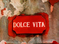 Old orange 'Dolce Vita' sign on a wall in Italy