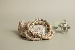 Two bracelets made of natural jasper stones beads isolated on pastel beige background. Handmade jewelry. Woman exoteric accessories. Talismans and amulets.