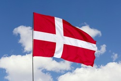 Denmark flag isolated on the blue sky with clipping path. close up waving flag of Denmark. flag symbols of Denmark.