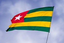 Togo flag isolated on sky background. National symbol of Togo. Close up waving flag with clipping path.
