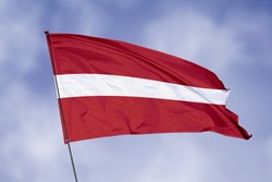 Latvia flag isolated on sky background. National symbol of Latvia. Close up waving flag with clipping path.