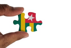 Hand holding piece of jigsaw puzzle with flag of Togo. Jigsaw puzzle of Togo flag on white background.