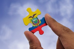 Hand holding piece of jigsaw puzzle with flag of Ecuador. Jigsaw puzzle of Ecuador flag on sky background.