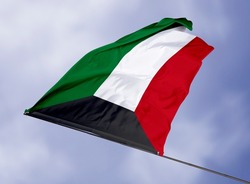 Kuwait's flag is isolated on a sky background. flag symbols of Kuwait. close up of a Kuwaiti flag waving in the wind.