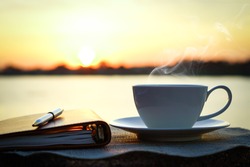 Silhouettes of sunrise morning coffee with a note and a pen