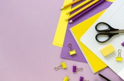 Flat lay of yellow and lilac school supplies on a color background. Space for text