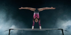 Female gymnast doing a complicated trick on gymnastic horizontal bar.