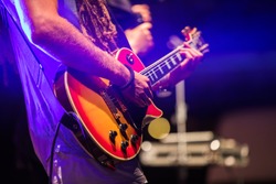 Guitarist playing on electric bass guitar on stage. Colorful, soft focus and blur background.