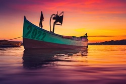 2022 concept. Fishing boat on shore and ripple sea water on dramatic colorful sunset