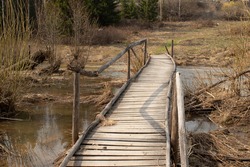 Rustic wooden rickety bridge during early spring floods. Bridge over a flooded stream in Siberia, Russia