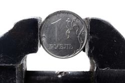 Coin one Russian ruble clamped by a black metal vice isolated on white background. Concept of financial and business problems. Russia economy under global sanctions