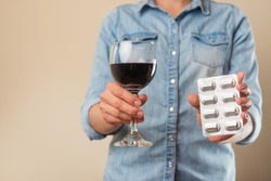 A girl holds a pill with a glass of wine, a ban on drugs for alcohol, the choice of treatment or alcohol
