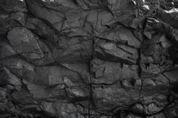 Black rock, stone, textured. Background for design. Hard light.