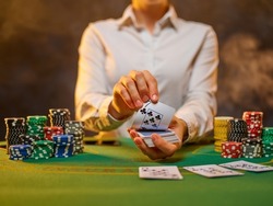 The girl of the croupier lays out the cards on the green cloth of the poker table. Stacks of chips. Casino, gambling, poker, gambling business, leisure, nightclub, hobby.