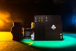 Poker cards and chips on the green cloth of the poker table. Yellow background. Focusing on the foreground. There are no people in the photo. Casino, gambling business, poker, game strategy.