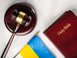 The gavel of the judge on the book and the flag of Ukraine, on a white table.Justice.The Hague court.Stop the war and justice.Russian invasion.For news and media