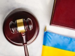 The gavel of the judge on the book and the flag of Ukraine, on a white table.Justice.The Hague court.Stop the war and justice.Russian invasion.For news and media