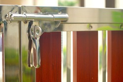 Close up door lock of stainless steel and wooden gate. Modern style. Red and silver. Protect you house. 