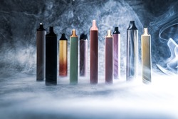 multicolored electronic cigarettes vape on dark background with smoke. High quality photo