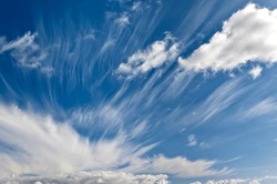 Cirrus and cumulus clouds ruffled by storm against blue sky