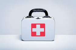 Tin first aid kit with cross emblem on grey background